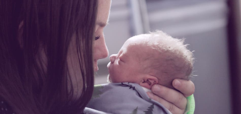 Een vrouw die een pasgeboren baby voorzichtig vasthoudt