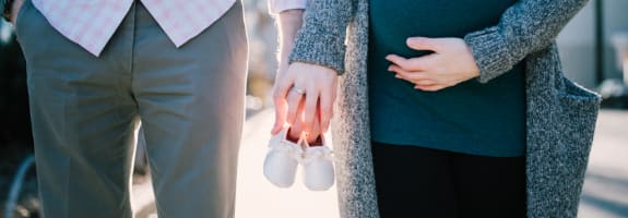 Twee mensen die naast elkaar lopen en samen babyschoentjes vasthouden