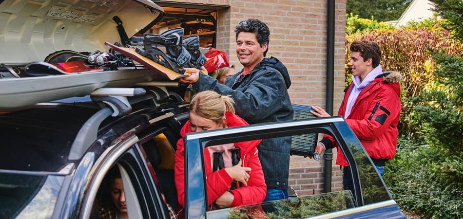 Gezin van drie mensen die de auto inpakken voor de wintersportvakantie