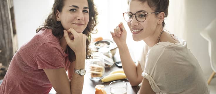 Twee vriendinnen zitten aan tafel. Zij huren samen een woning en sloten een overlijdensrisicoverzekering af.