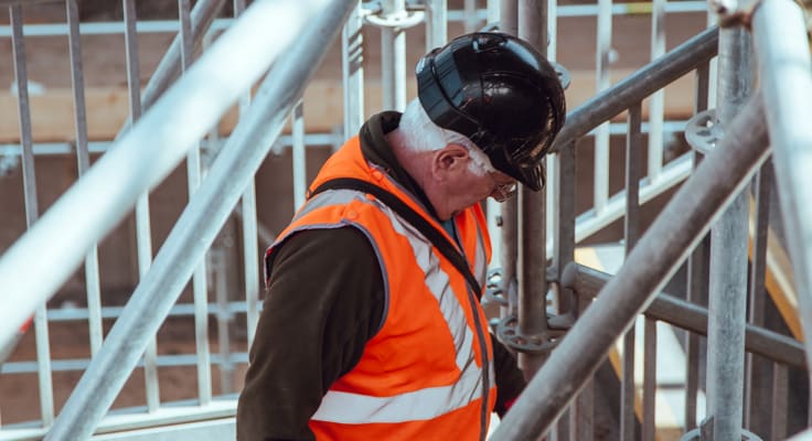 Man met helm en veiligheidsvest op een steiger