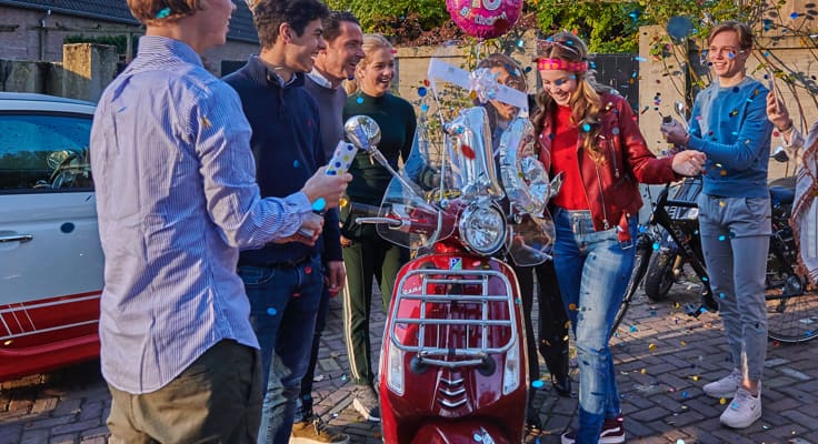 Meisje wordt 16 jaar en krijgt scooter van vrienden die erbij staan.