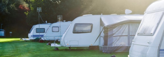 Caravans op een camping in een bosrijke omgeving. Met de Caravanverzekering van Interpolis kunt u uw caravan verzekeren tegen schade en diefstal.