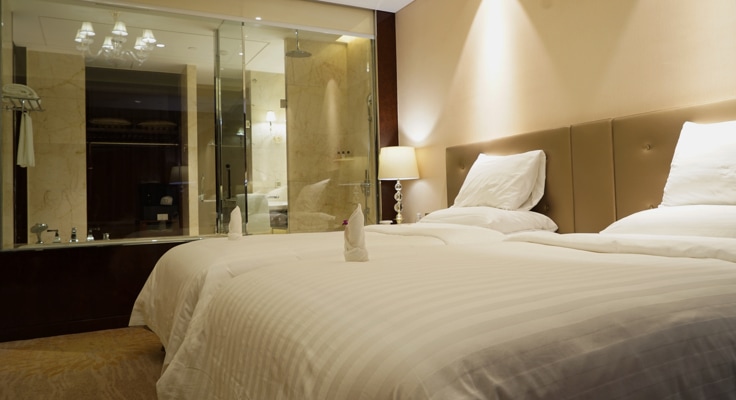 Opgemaakt bed in hotelkamer. Met de Doorlopende Annuleringsverzekering kunt u het onverwachts annuleren of het afbreken van een reis of vakantie verzekeren.