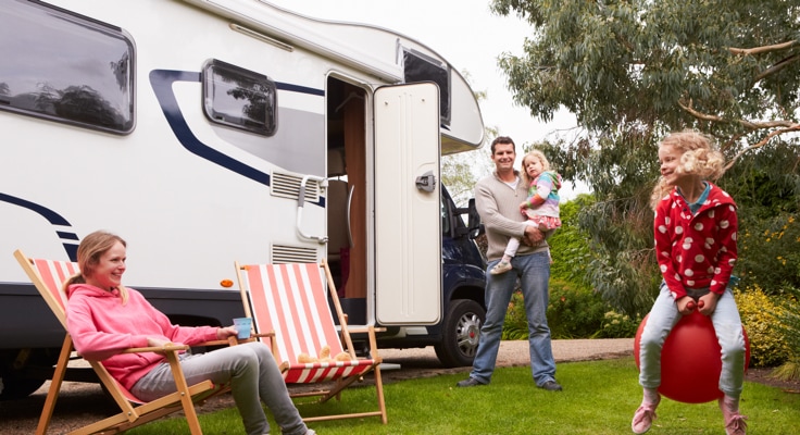 Vader met kinderen voor camper in bosrijke omgeving. Met de Camperverzekering van Interpolis kunt u uw camper verzekeren tegen schade en diefstal.