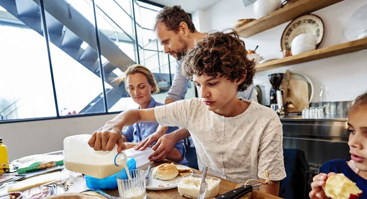 Gezin zit aan tafel en eet ontbijt. Met de overlijdensrisicoverzekering voorkomt uw financiële zorgen voor wie u lief is.