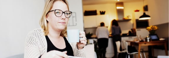 Vrouw zit op de bank met een IPad in de woonkamer en drinkt koffie. Met de rechtsbijstandverzekering van Interpolis verzekert u rechtshulp en juridisch advies bij conflicten.