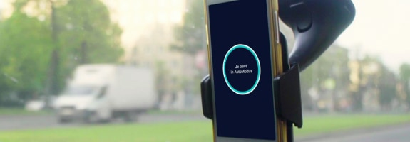 Smartphone in een telefoonhouder in een auto, waarop de AutoModus app is geopend