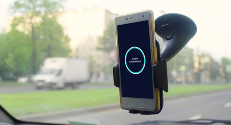 Smartphone in een telefoonhouder in een auto, waarop de AutoModus app is geopend