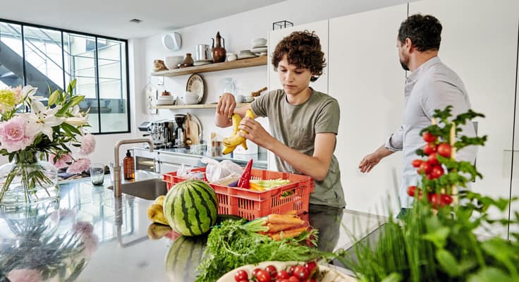 Vader en zoon ruimen boodschappen op in de keuken. Met de woonhuisverzekering van Interpolis verzekert u uw huis tegen schade of inbraak.