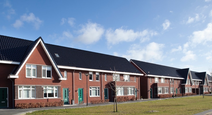 Woonwijk met rijtjeshuizen en een groenstrook ervoor. Met een Woonhuisverzekering of Opstalverzekering verzekert u schade en schade door diefstal, zoals braakschade.
