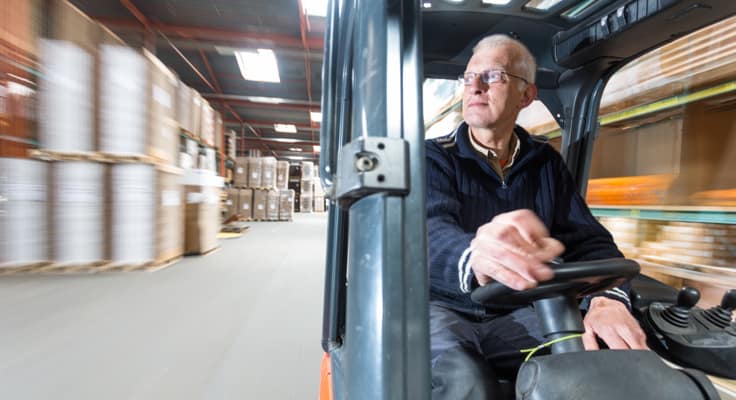 Man rijdt op heftruck rond in magazijn en kijkt om zich heen. Met de rijdend werkmaterieelverzekering van Interpolis verzekert u grond- en graafwerkzaamheden en inzittenden van het werktuig.