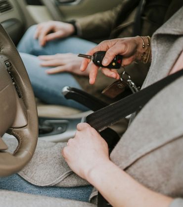 Vrouw zit achter het stuur van een auto met de autosleutels in haar hand