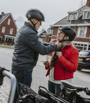 Man en vrouw staan naast e-bikes en zetten fietshelmen op.