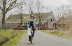 Een persoon fietst op een weg in het buitengebied.