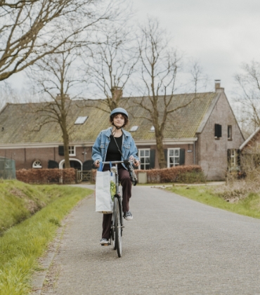 Een persoon fietst op een weg in het buitengebied.