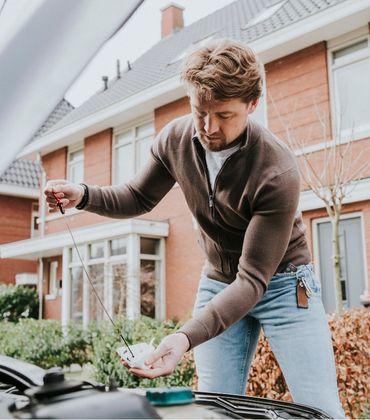 Een man controleert het oliepeil van een auto