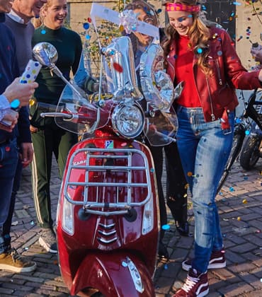 Een groep mensen om een scooter die iemand krijgt voor zijn verjaardag