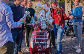 Een groep mensen om een scooter die iemand krijgt voor zijn verjaardag