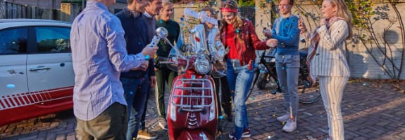 Een groep mensen om een scooter die iemand krijgt voor zijn verjaardag