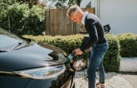Man steekt de oplaadkabel in zijn elektrische auto