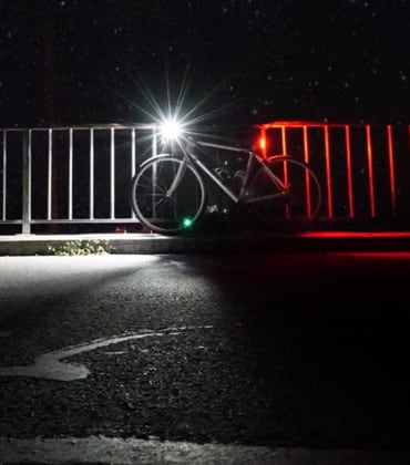 Een fiets met brandend voorlicht en achterlicht die tegen een hek aanstaat