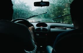 Voorruit van een auto met ruitenwissers tijdens een regenbui