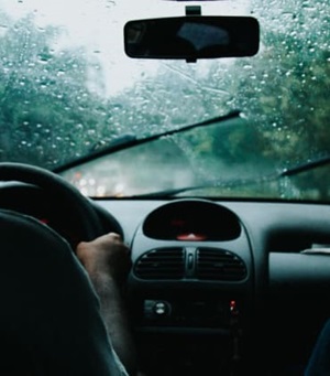 Voorruit van een auto met ruitenwissers tijdens een regenbui