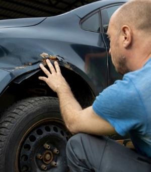 Man bekijkt de schade aan zijn auto.