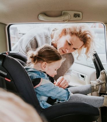 Een vrouw zet een meisje in een autostoel