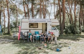 Een gezin zit voor de camper