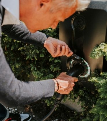 Een persoon steekt de stekker van een elektrische auto in een oplaadpunt. 