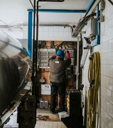 Een installateur verricht werkzaamheden in de meterkast van een bedrijf.