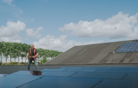 De inspecteur staat op het dak van een bedrijfsgebouw en keurt de zonnepaneleninstallatie. 