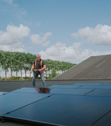 De inspecteur staat op het dak van een bedrijfsgebouw en keurt de zonnepaneleninstallatie. 