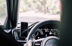 Dashboard van auto met naast het stuur een telefoon in Automodus