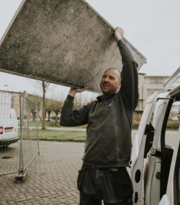 ondernemer in de bouw die een steigerplaat tilt