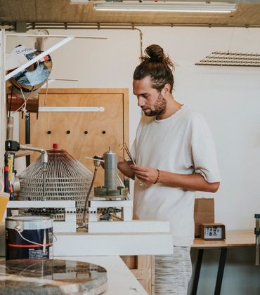 Een man met een wit t-shirt staat in een creatieve werkplaats.