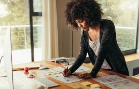 Vrouw staat aan haar bureau te werken