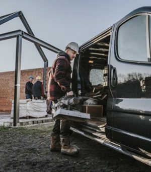 Een foto van een man die gereedschap in een zwarte werkbus legt.