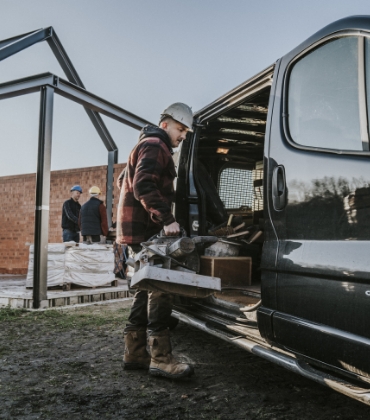 Een foto van een man die gereedschap in een zwarte werkbus legt.