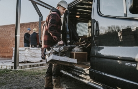 Een foto van een man die gereedschap in een zwarte werkbus legt.