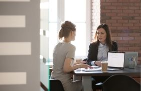 Twee vrouwen achter de laptop in overleg met elkaar