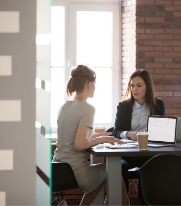 Twee vrouwen achter de laptop in overleg met elkaar