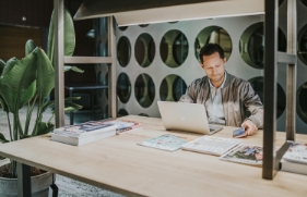 Een man werkt in een industriële kantooromgeving op zijn laptop.