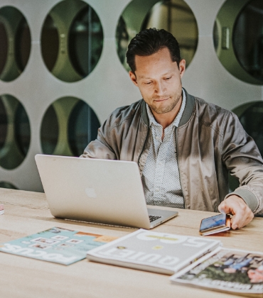 Een man werkt in een industriële kantooromgeving op zijn laptop.