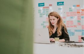 Een vrouw werkt in een kantooromgeving op haar laptop.