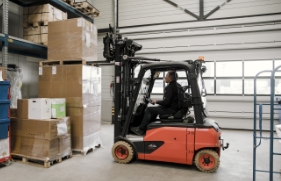 Een persoon gebruikt een heftruck om pallets op elkaar te stapelen.