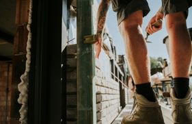 Schoenen van een bouwvakker naast een muurtje dat hij bouwt