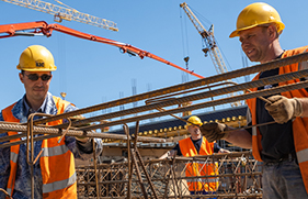 Mannen met helm op en veiligheidshestje aan, aan het werk op de bouw